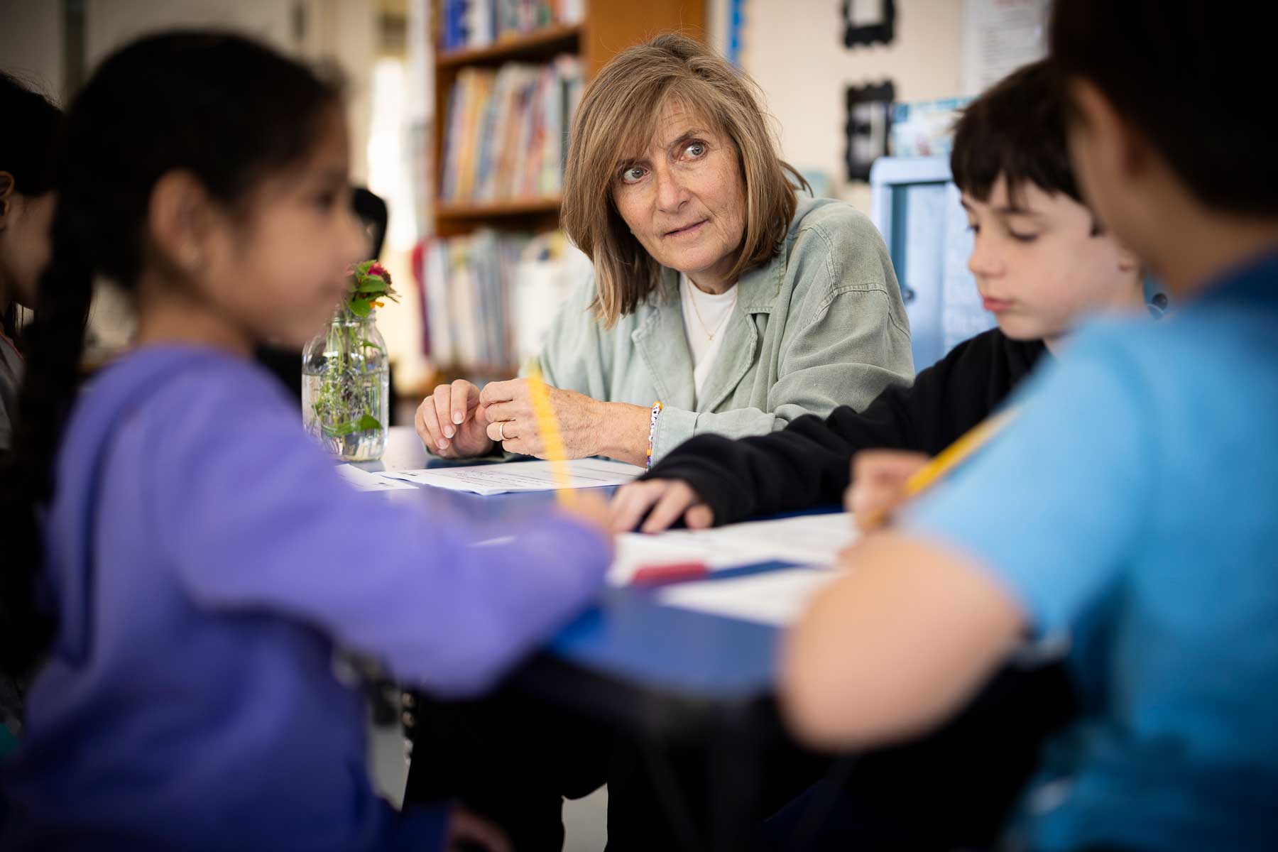 A teacher sits surrounded by three students during a math lesson